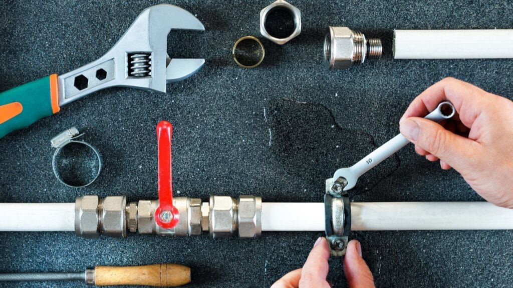 Plumber repairing a pipe valve with an adjustable wrench in Kennesaw