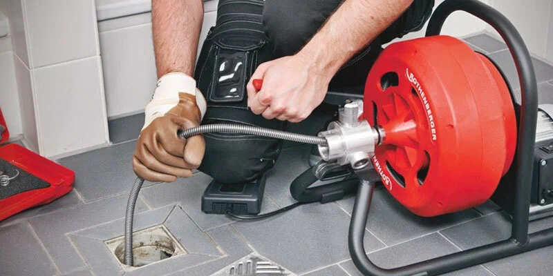 Plumber using a drain-cleaning machine in Kennesaw