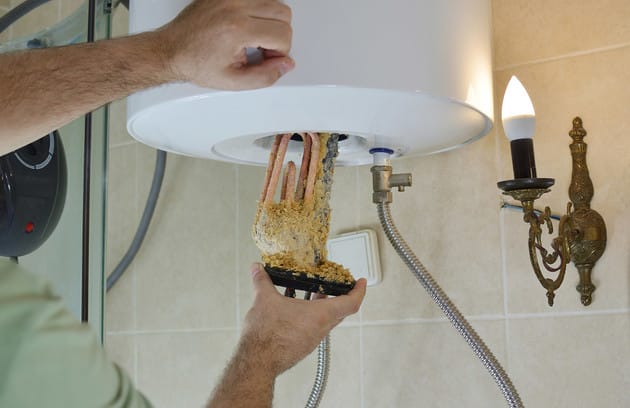 Technician removing mineral buildup from a water heater in Kennesaw