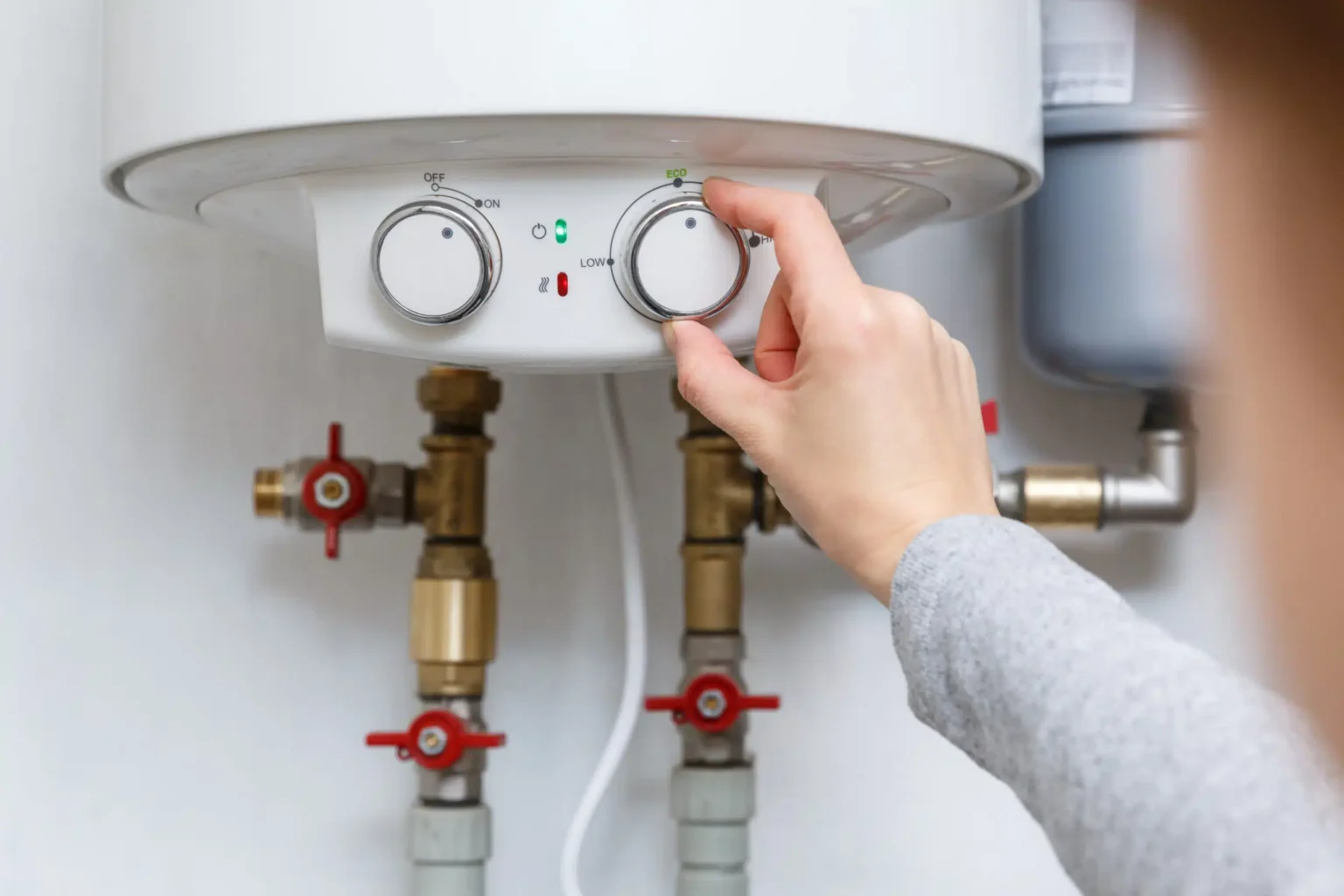 Homeowner adjusting the temperature controls on a water heater in Kennesaw